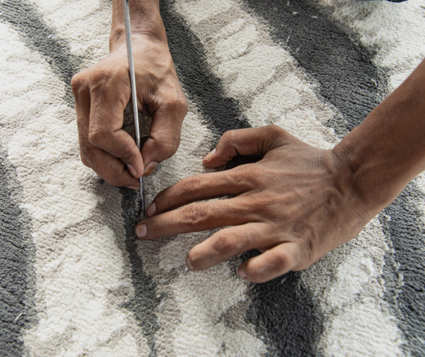 Close-up of an artisan's hands checking a Tibetan rug.
